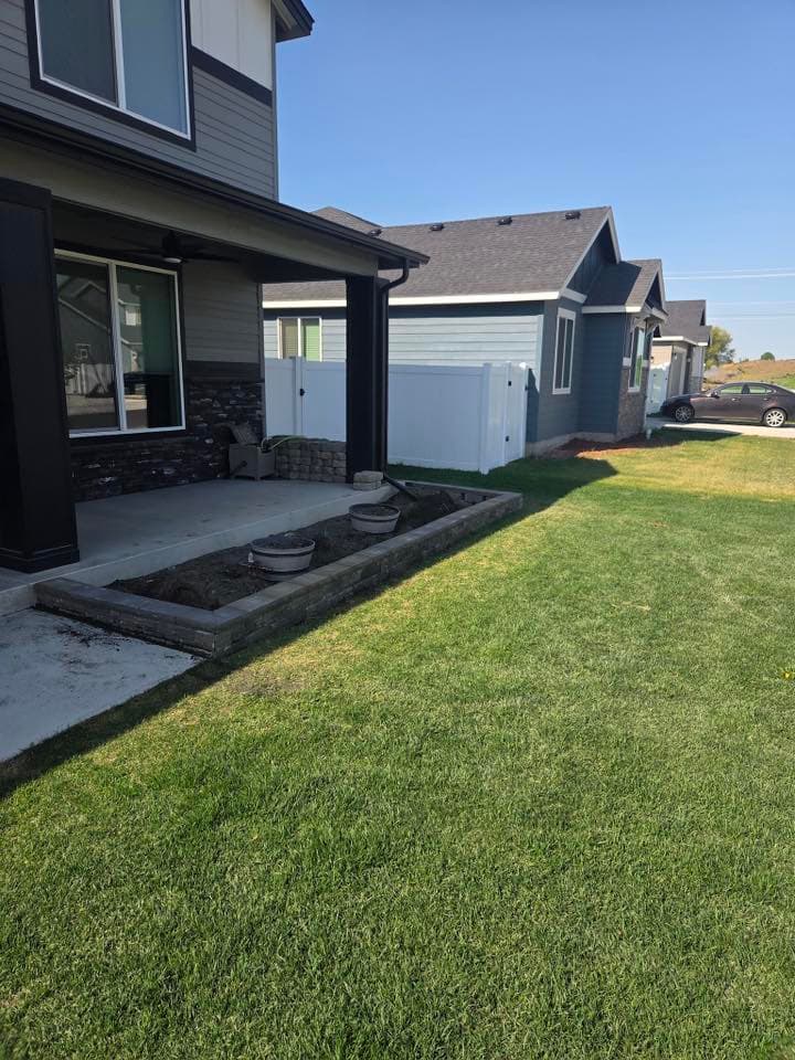Modern house exterior with landscaped lawn and planters, featuring clear blue sky and neighboring homes.